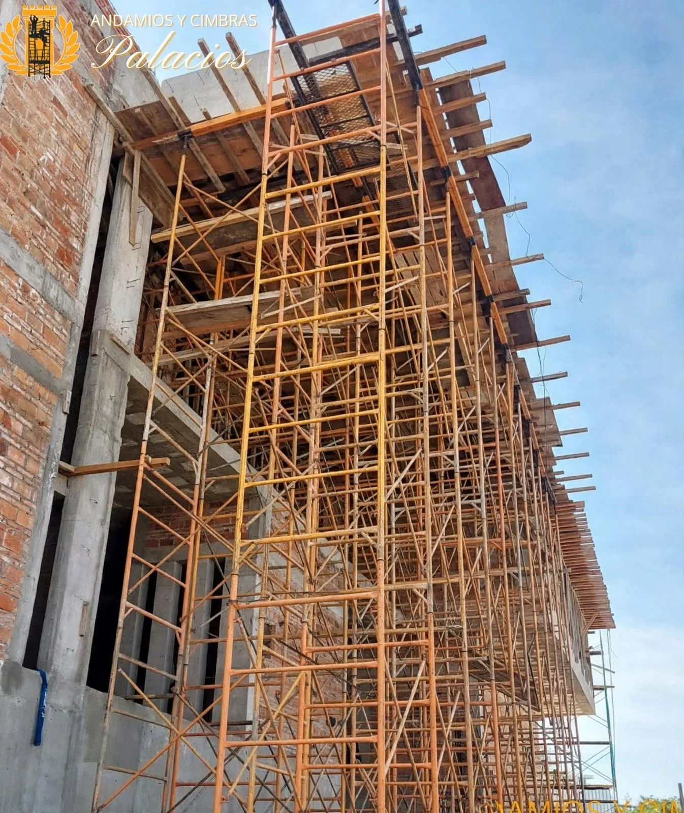 Andamios y cimbra junto a un muro en construcción