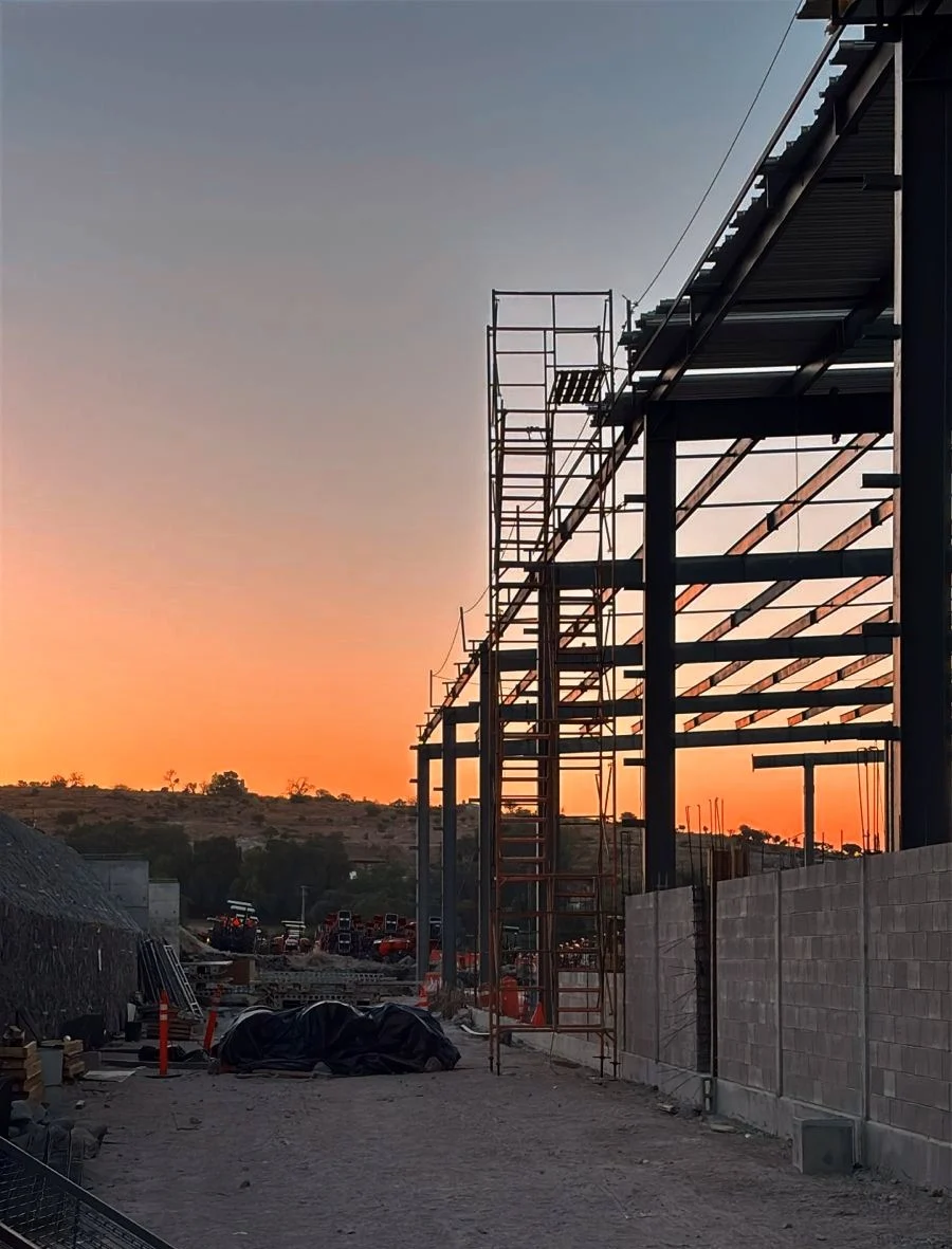 Torre de andamios junto a una estructura metálica al atardecer